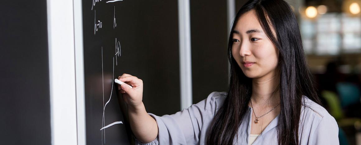 Graduate student writing on a white board