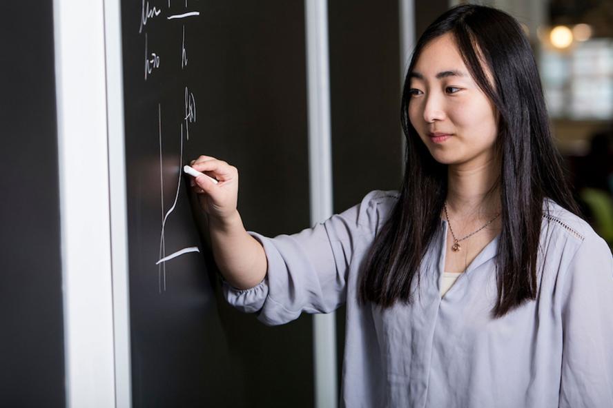 Graduate student writing on a white board